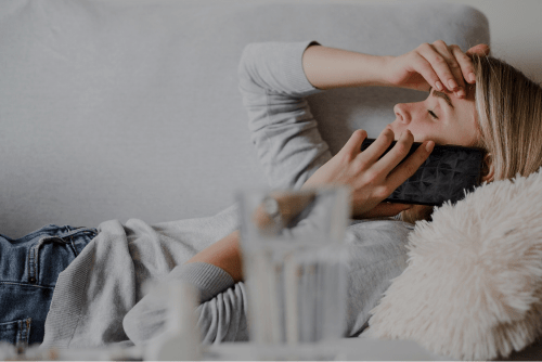 A woman with her hand on her head while on the phone due to poor indoor air quality