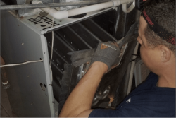 A Sarasota heater repair technician - Streamline Heating and Air A Sarasota heater repair technician with his hands on the inside of a heater unit