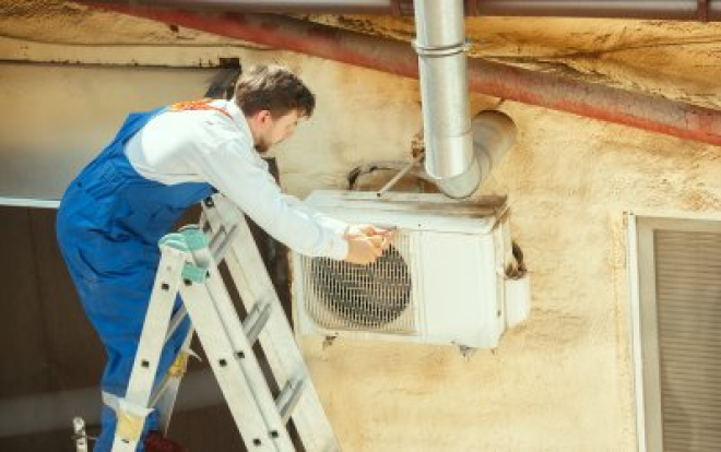 A person working on an outdoor A/C unit