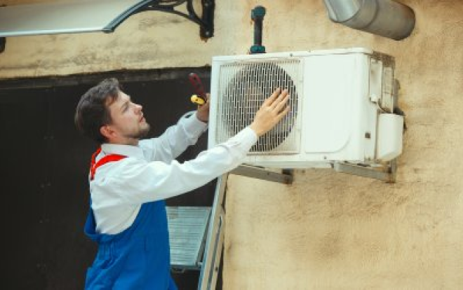 An air conditioner person working on an outdoor AC unit