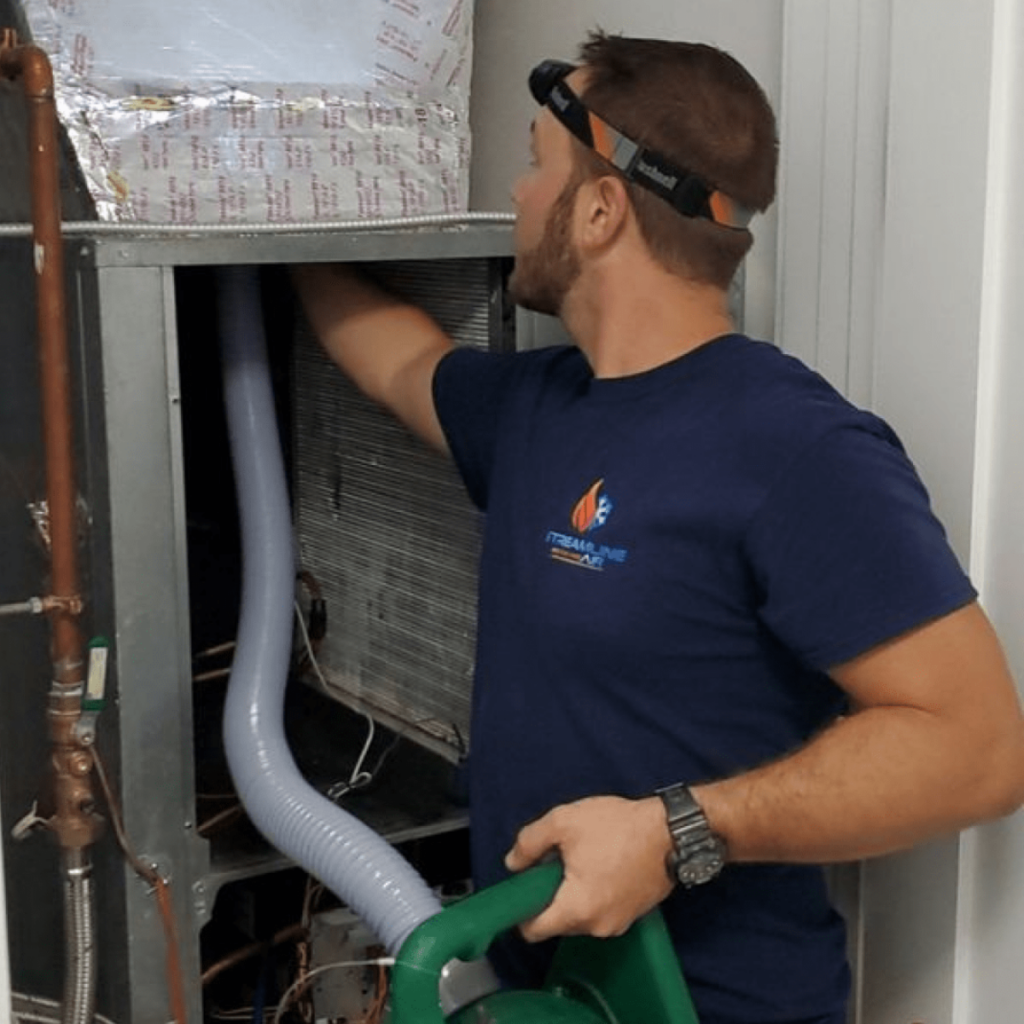 An HVAC service technician cleaning out air ducts in an HVAC system