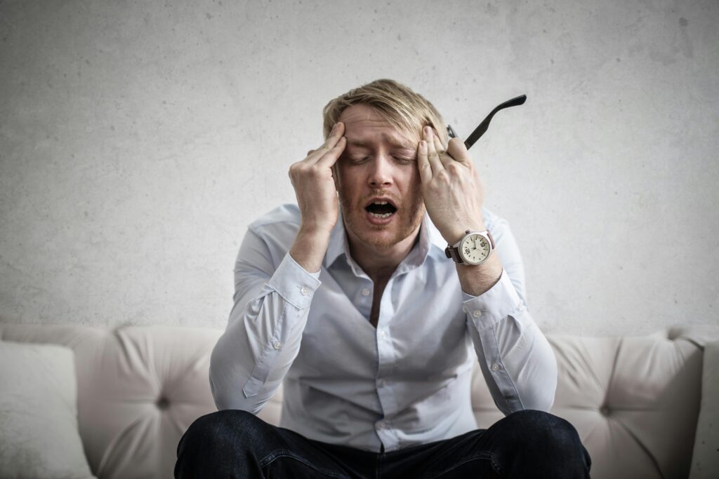 A person with their hands on the temples of their head sweating