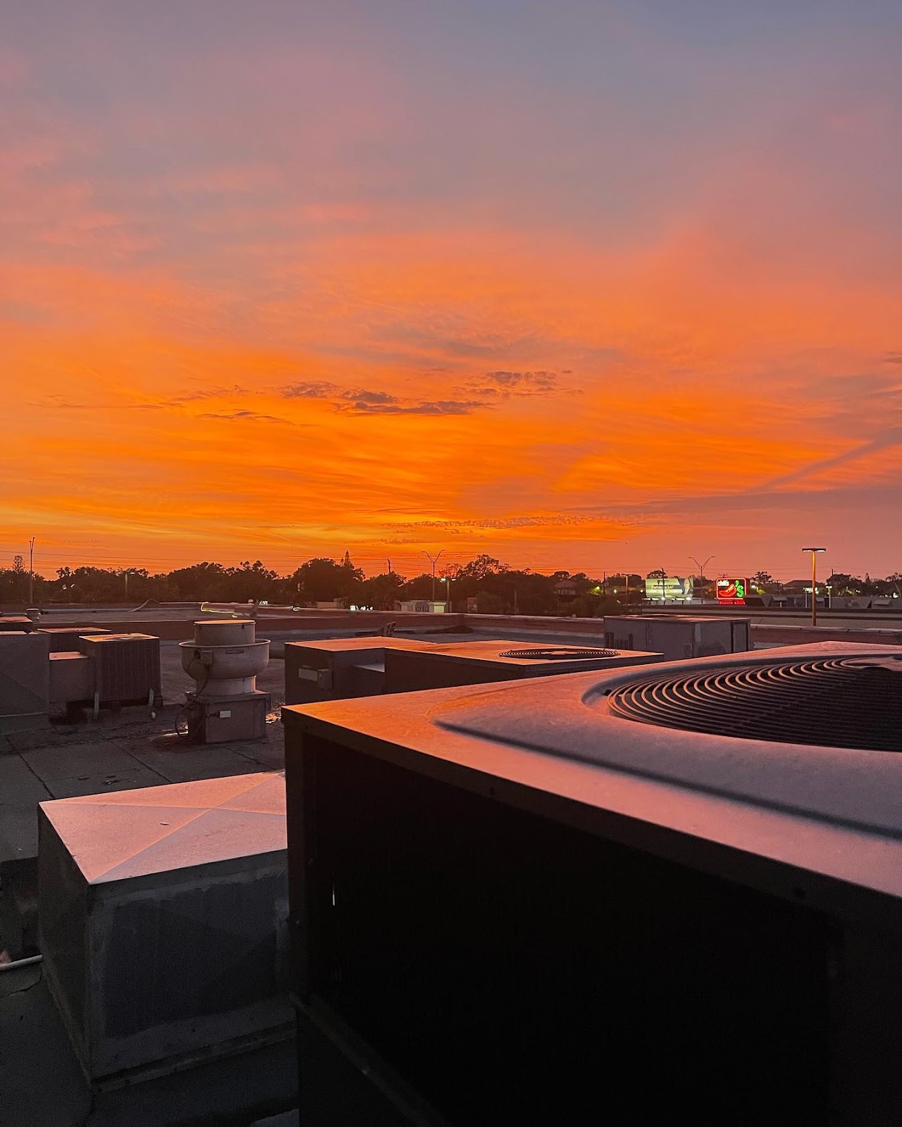 A picture of a sunset with an air conditioning unit on the roof