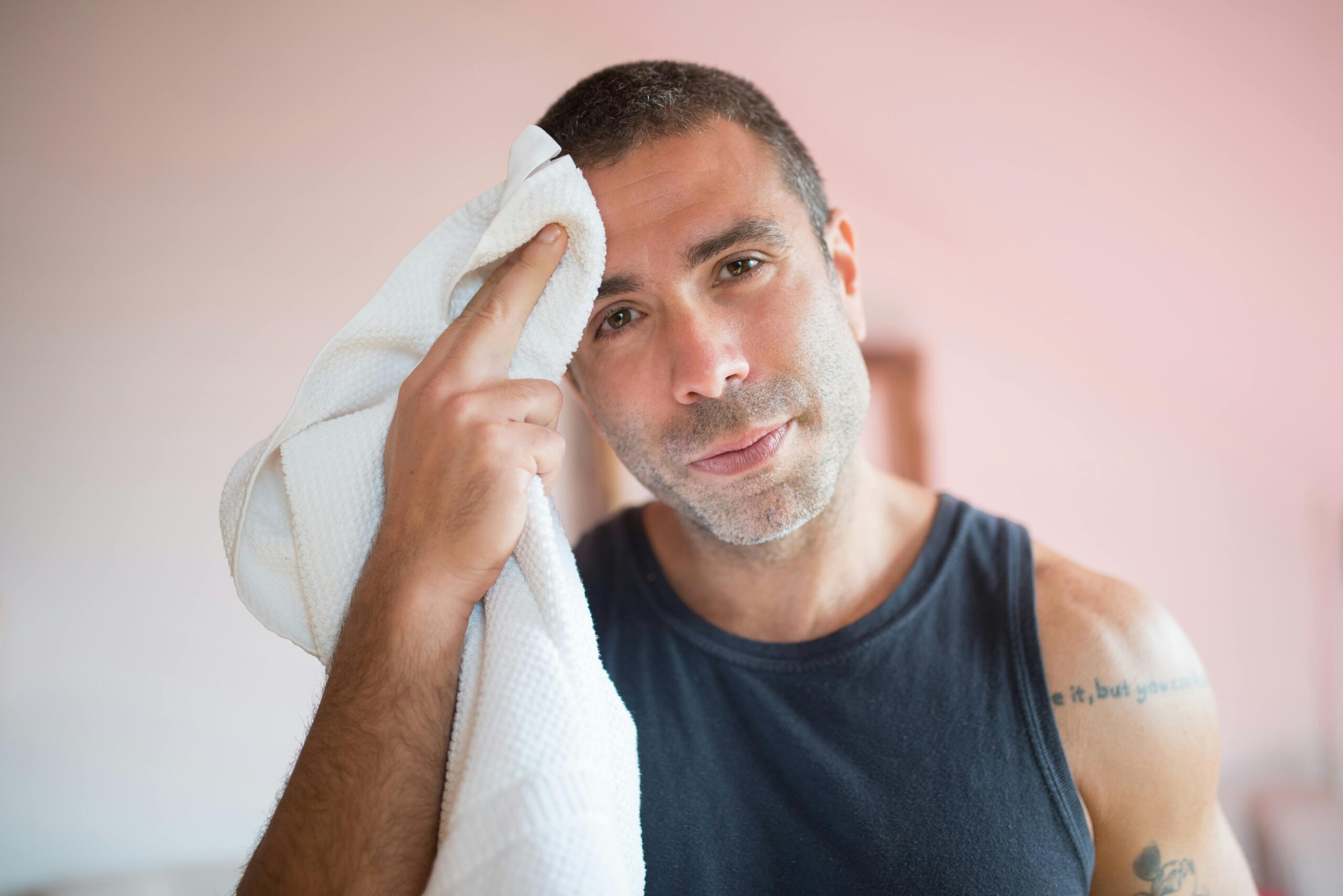 A person with a towel to their head because an air conditioner is not cooling enough